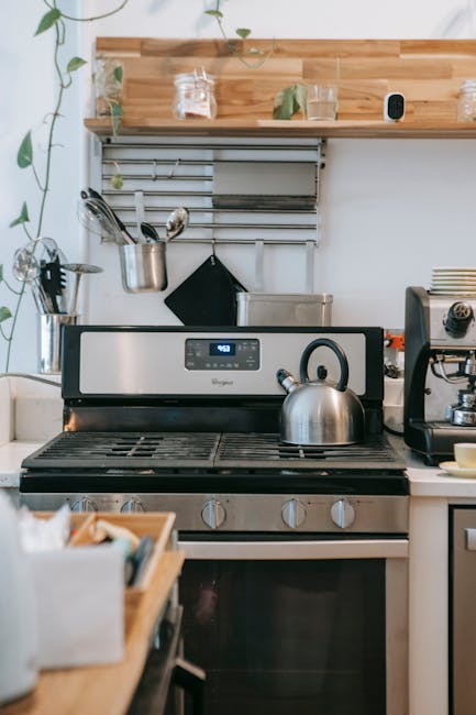 A person wearing blue and yellow rubber gloves is cleaning the interior surface of an oven with a purple microfiber cloth, which is visibly wiping away cleaning solution and grease. The oven's interio